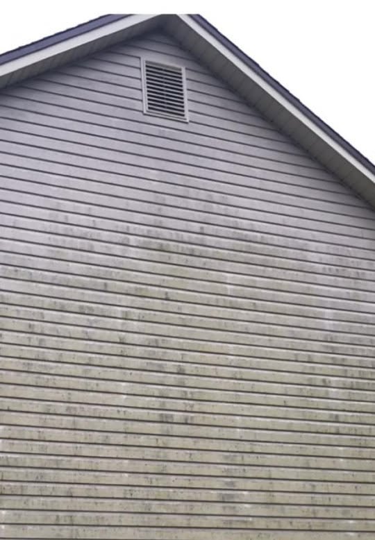 Gable end of house with gray vinyl siding and roof vent