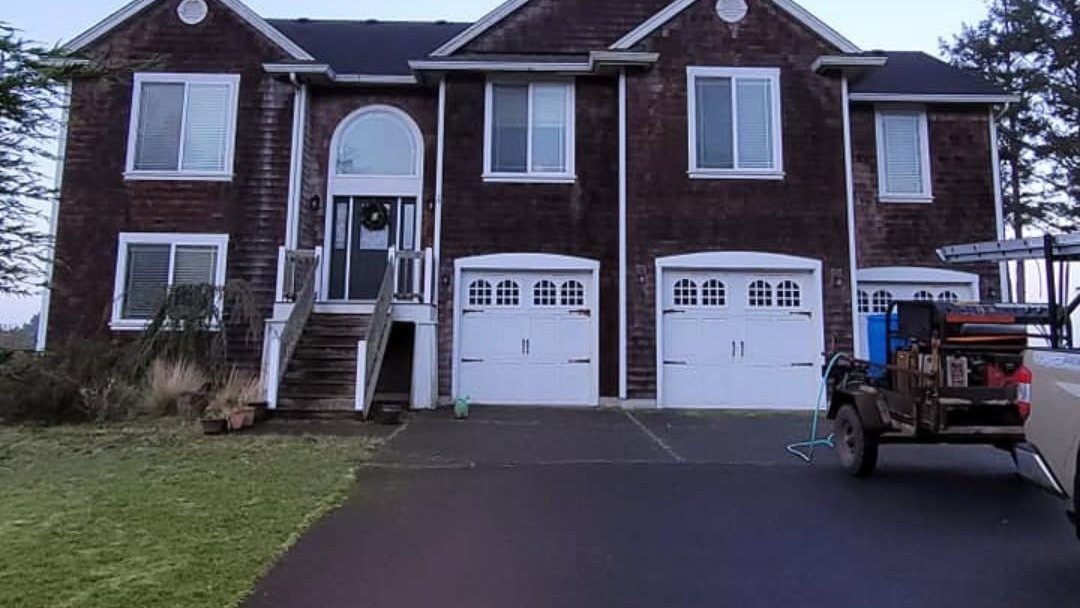 Brick residential home with two white garage doors and service truck in driveway