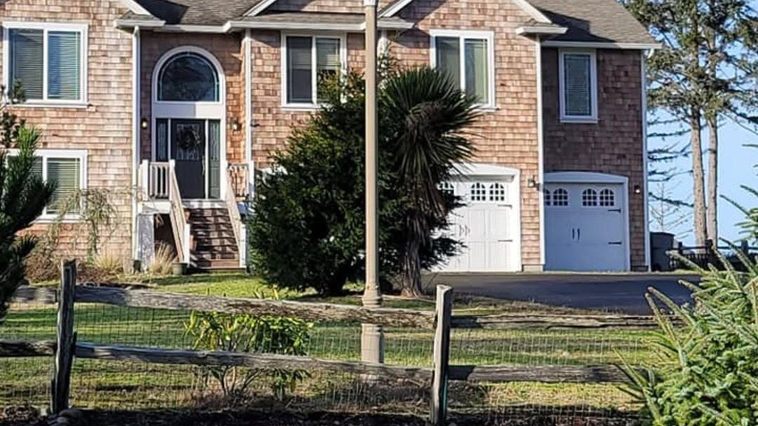 Brick residential home with two-car garage, front porch, and wooden fence