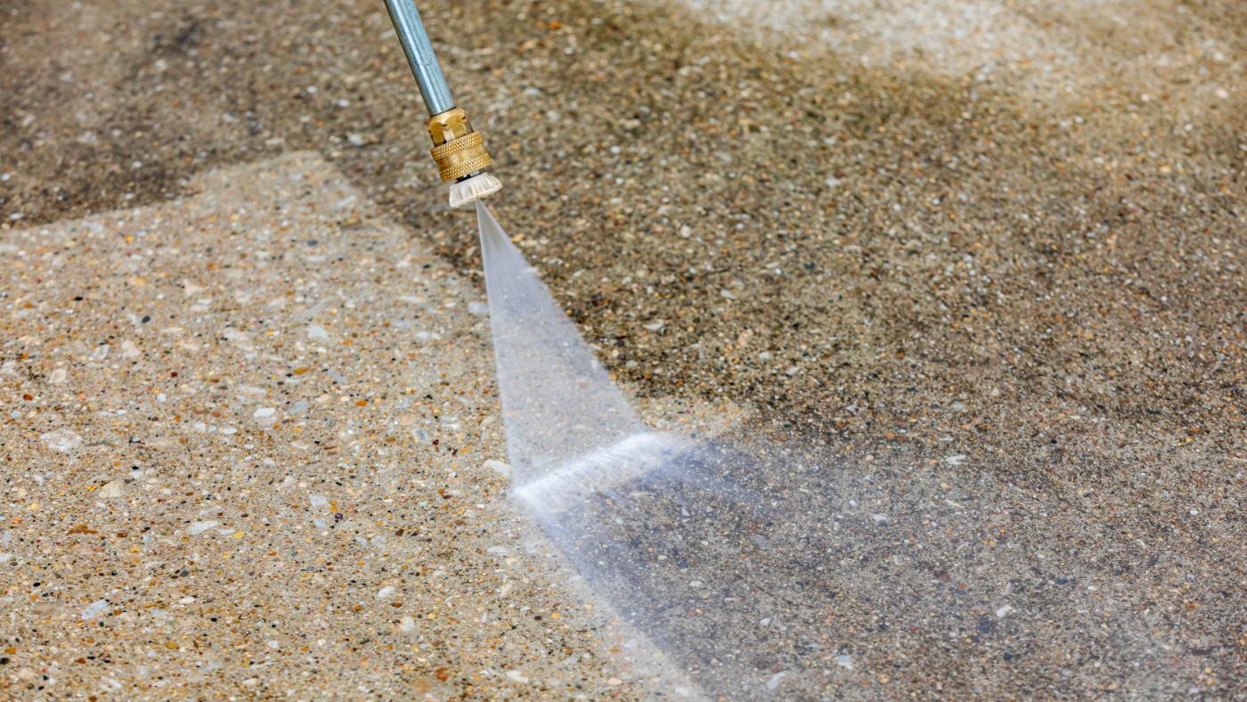 Pressure washer spray cleaning concrete surface with brass nozzle attachment