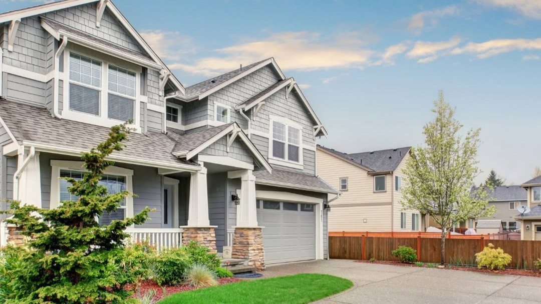 Modern two-story residential home with gray siding, white trim, and attached garage in suburban neighborhood