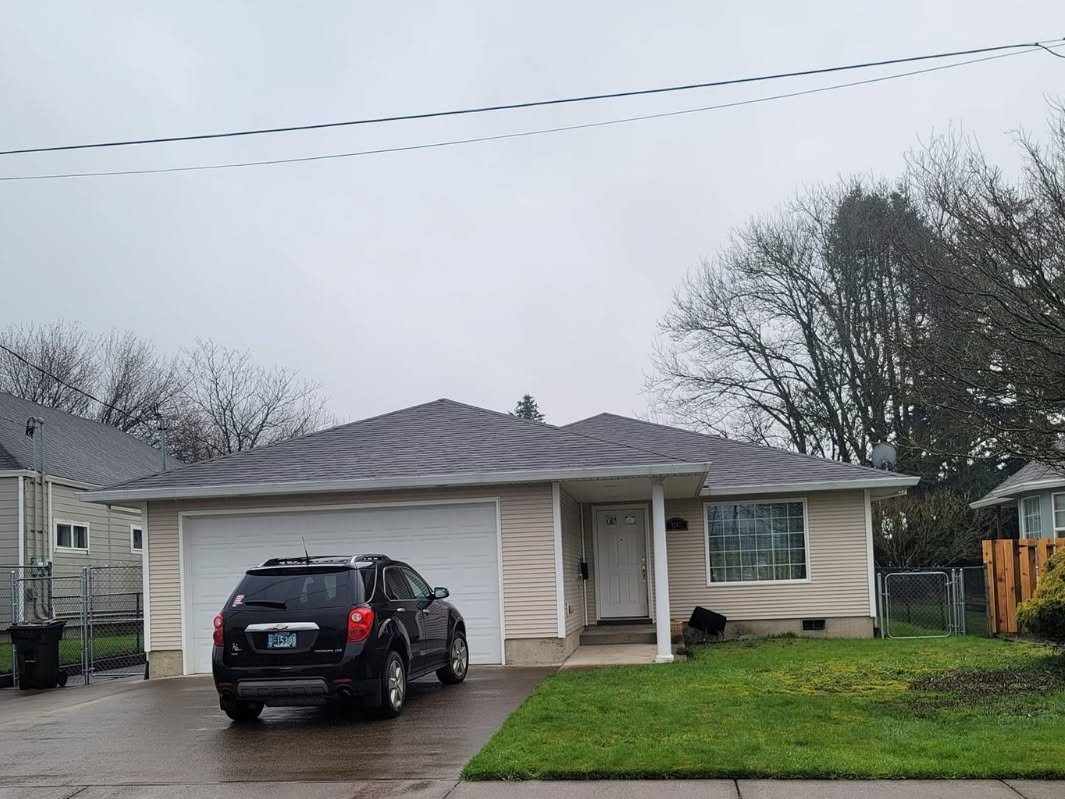 Single-story beige house with gray roof, white garage door, and dark SUV in driveway